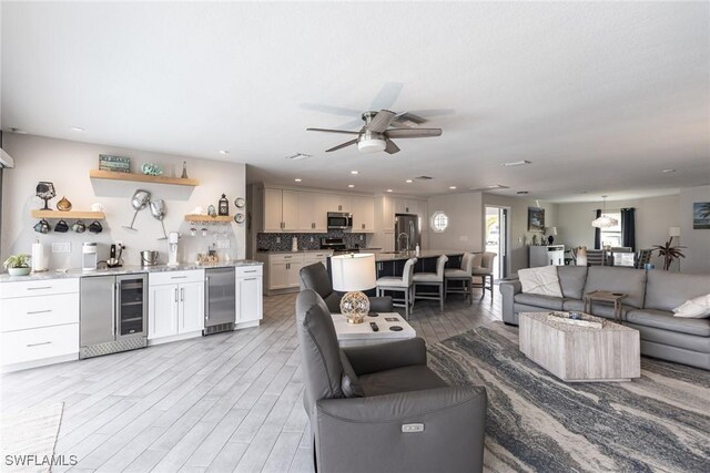 living area with a dry bar, a ceiling fan, wine cooler, light wood-style floors, and recessed lighting