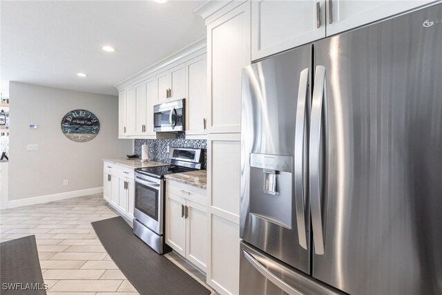 kitchen featuring recessed lighting, decorative backsplash, appliances with stainless steel finishes, white cabinetry, and baseboards