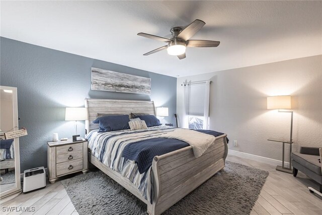 bedroom featuring light wood-style floors, baseboards, and a textured wall