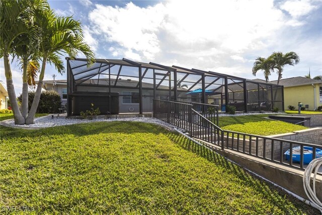 rear view of property with glass enclosure and a yard