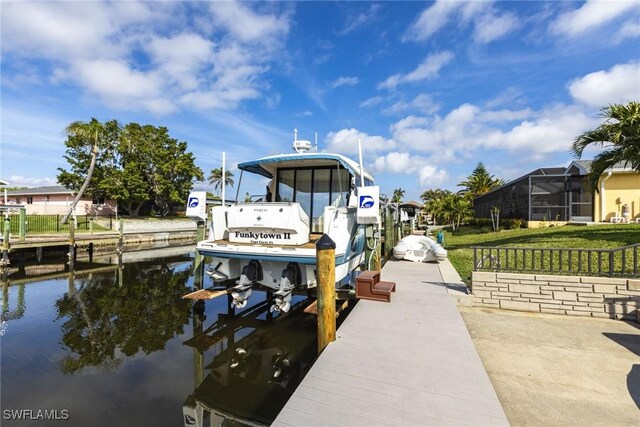 dock area with a water view, a lawn, and boat lift