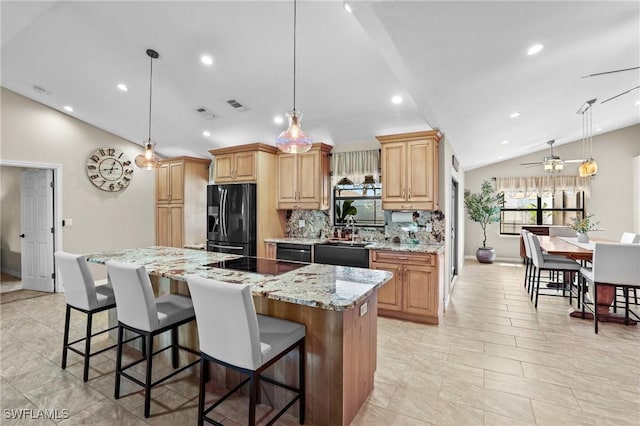 kitchen with a breakfast bar, lofted ceiling, a sink, a kitchen island, and black appliances