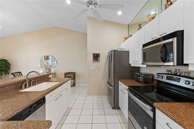 kitchen featuring light tile patterned flooring, stainless steel appliances, a sink, vaulted ceiling, and dark countertops