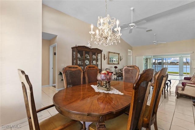 dining area featuring light tile patterned floors, a water view, high vaulted ceiling, baseboards, and ceiling fan with notable chandelier