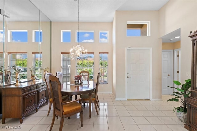 dining area with a chandelier, light tile patterned flooring, a towering ceiling, and baseboards