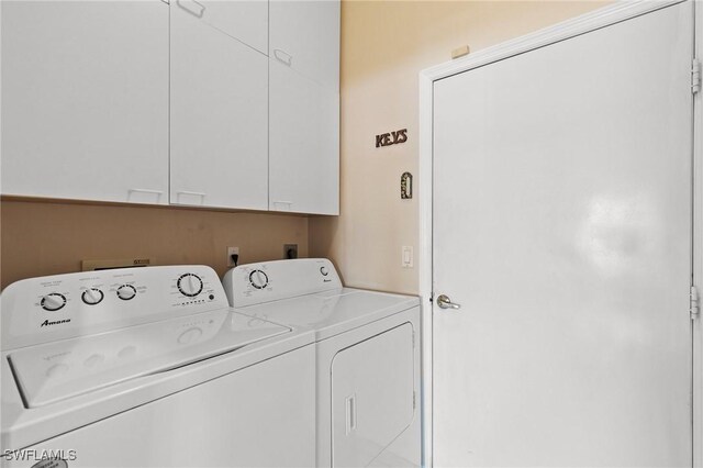 washroom featuring cabinet space and washer and clothes dryer