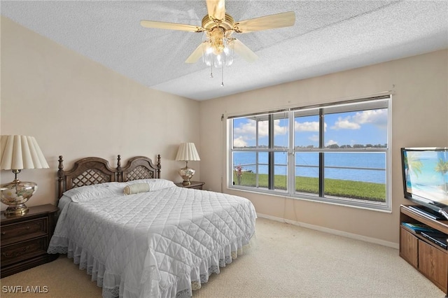 bedroom with light carpet, ceiling fan, a textured ceiling, and baseboards