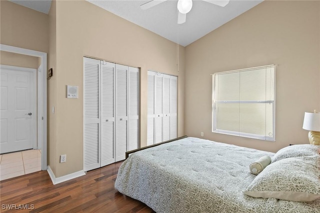 bedroom with lofted ceiling, wood finished floors, a ceiling fan, baseboards, and multiple closets