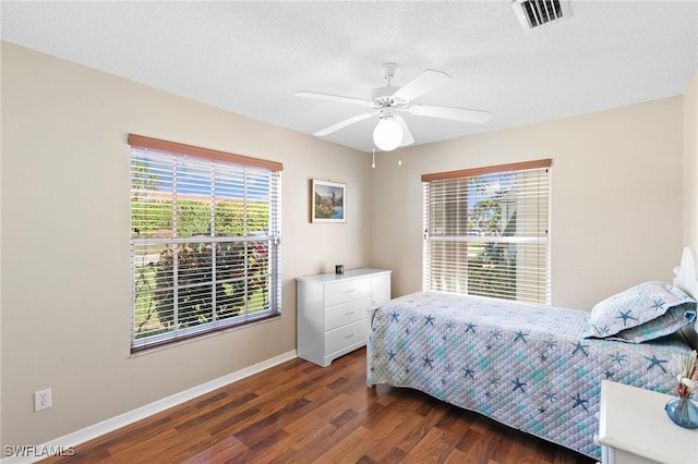 bedroom featuring baseboards, multiple windows, visible vents, and dark wood-type flooring