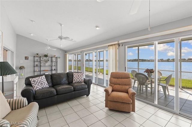 living area with light tile patterned floors, vaulted ceiling, a water view, and a ceiling fan