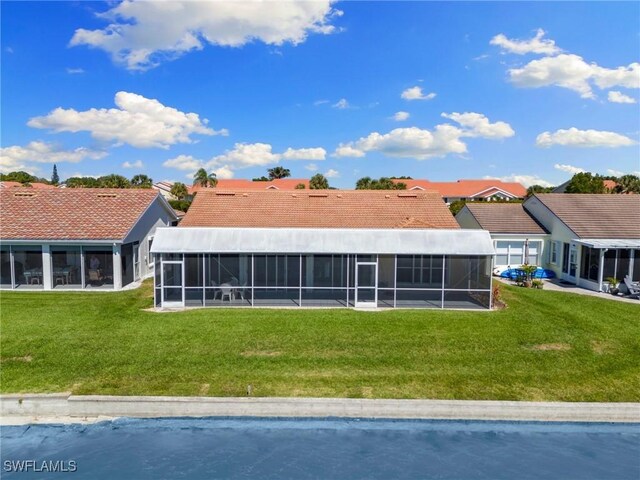 rear view of property featuring a sunroom, a tile roof, and a yard