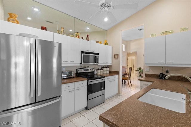 kitchen featuring light tile patterned floors, stainless steel appliances, a sink, a ceiling fan, and vaulted ceiling