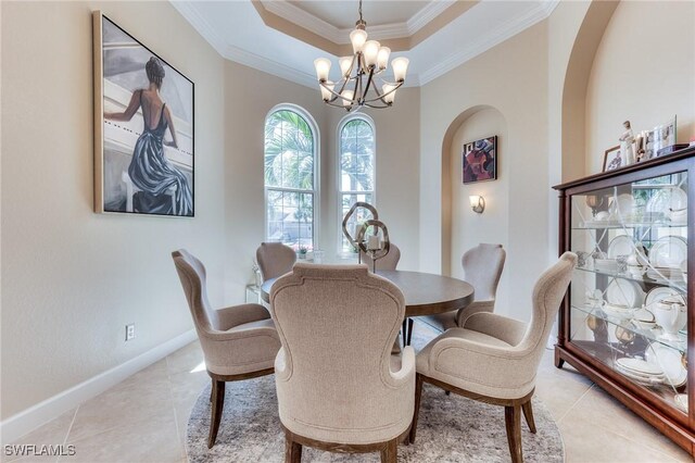 dining space with arched walkways, a notable chandelier, baseboards, ornamental molding, and a raised ceiling