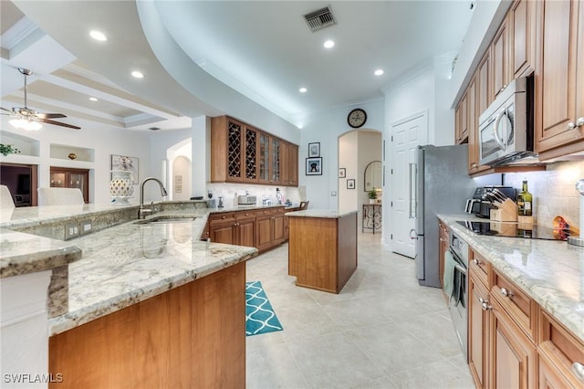 kitchen featuring light stone counters, arched walkways, a center island, appliances with stainless steel finishes, and a sink