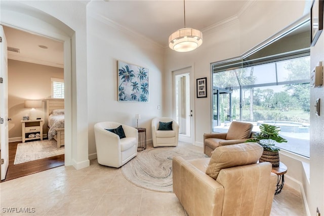 living area featuring light tile patterned floors, baseboards, visible vents, and crown molding