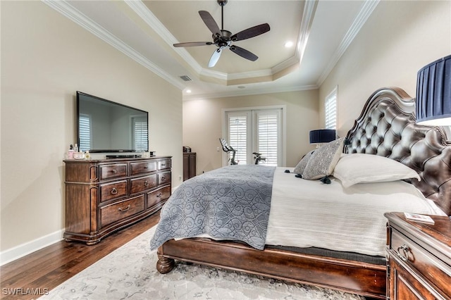 bedroom with visible vents, baseboards, ornamental molding, a tray ceiling, and dark wood finished floors