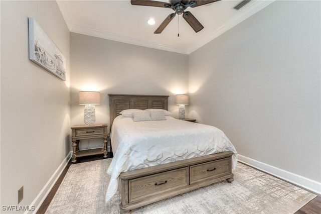 bedroom with visible vents, crown molding, baseboards, and wood finished floors