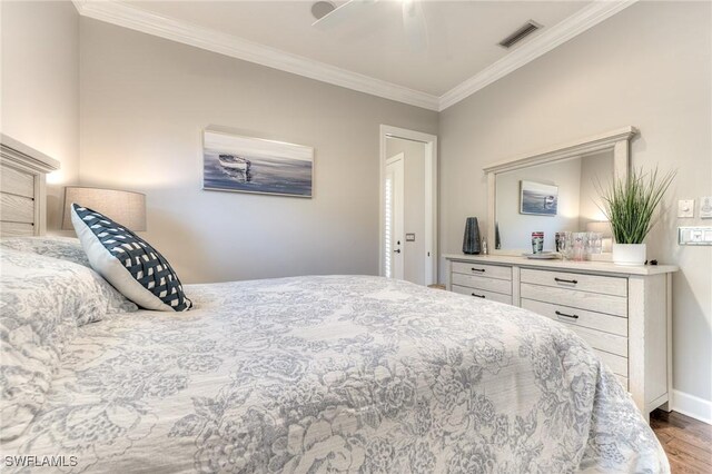 bedroom with baseboards, visible vents, crown molding, and wood finished floors