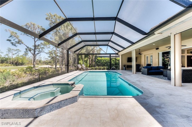 view of swimming pool featuring glass enclosure, outdoor lounge area, a pool with connected hot tub, a ceiling fan, and a patio area