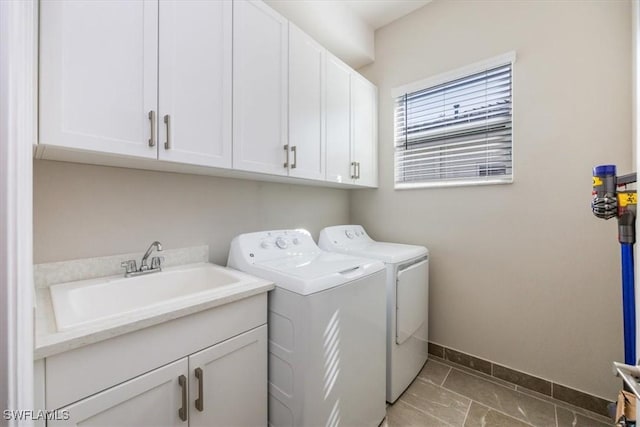 laundry area featuring cabinet space, separate washer and dryer, baseboards, and a sink