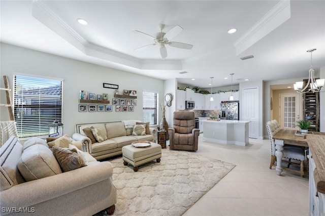 living room with ornamental molding, ceiling fan with notable chandelier, recessed lighting, light tile patterned flooring, and a raised ceiling