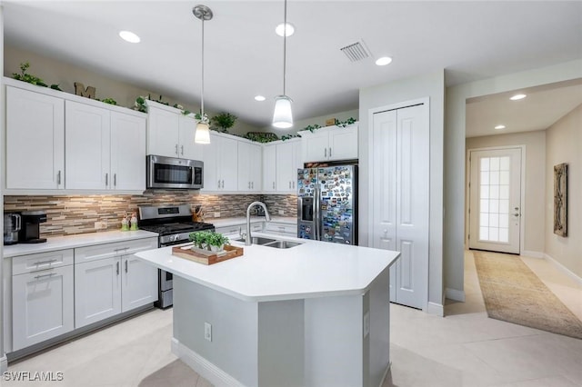 kitchen featuring backsplash, a center island with sink, light countertops, stainless steel appliances, and a sink