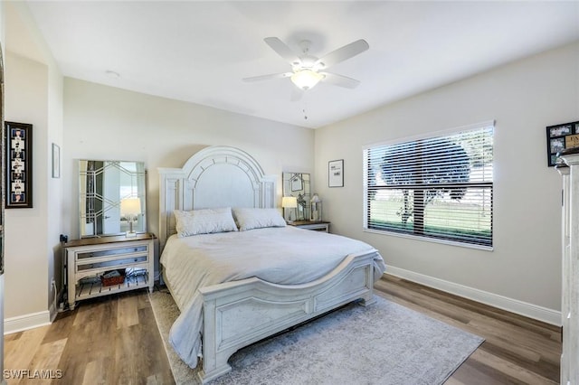 bedroom featuring baseboards, wood finished floors, and a ceiling fan