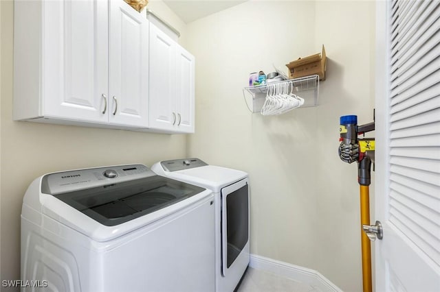 washroom with light tile patterned floors, cabinet space, independent washer and dryer, and baseboards