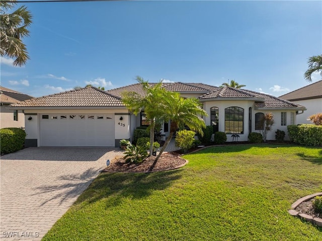 mediterranean / spanish house featuring a garage, a tiled roof, and stucco siding