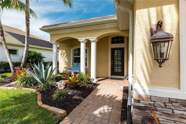 entrance to property featuring a porch and stucco siding