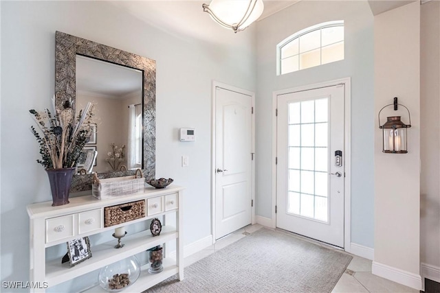 foyer featuring a healthy amount of sunlight, light tile patterned floors, and baseboards