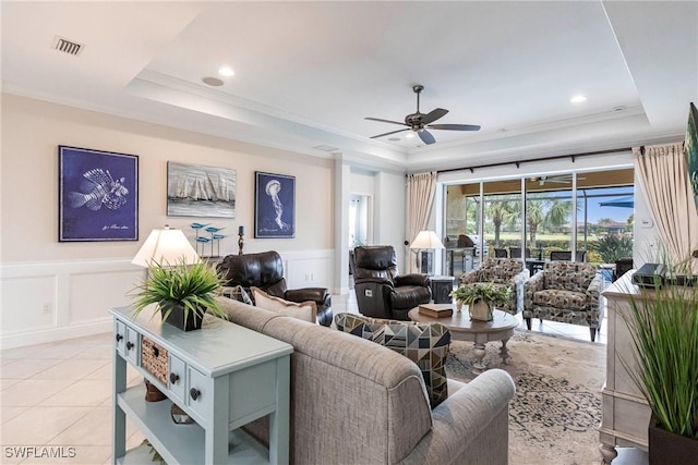 living area featuring a raised ceiling, visible vents, a wainscoted wall, and light tile patterned floors