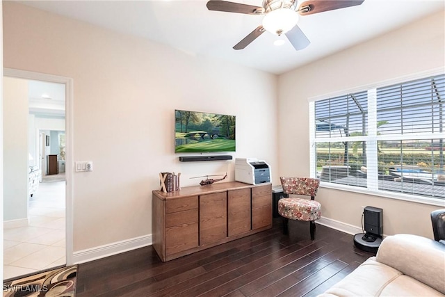 living area featuring dark wood-style flooring, a ceiling fan, and baseboards