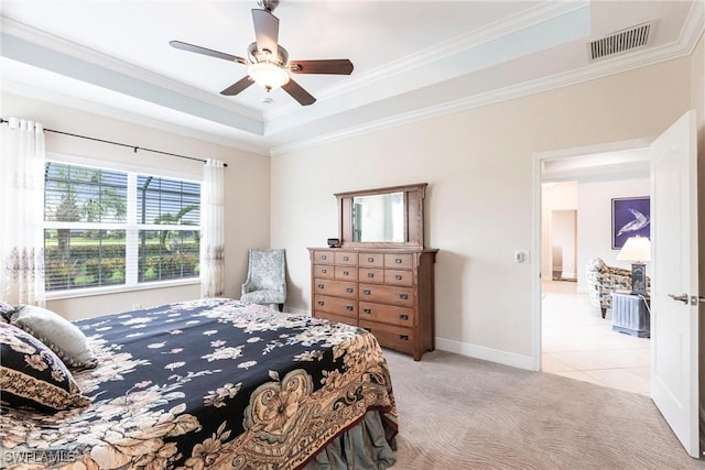 bedroom with baseboards, visible vents, light colored carpet, a tray ceiling, and crown molding