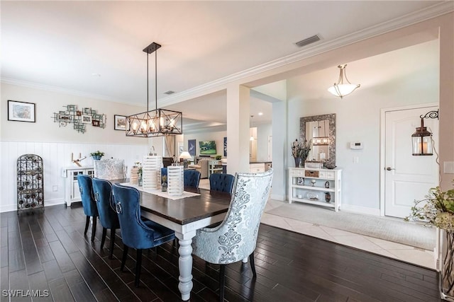 dining area with crown molding, dark wood finished floors, visible vents, an inviting chandelier, and baseboards