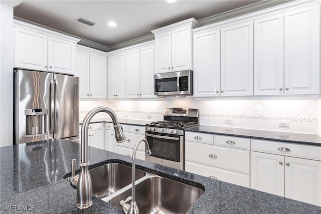 kitchen featuring stainless steel appliances, white cabinetry, a sink, and tasteful backsplash