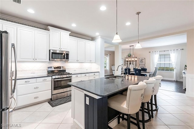 kitchen with stainless steel appliances, white cabinetry, a sink, and light tile patterned floors