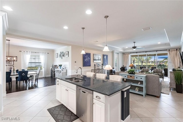 kitchen with a tray ceiling, light tile patterned floors, stainless steel dishwasher, open floor plan, and a sink