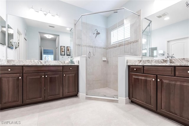 full bath featuring a sink, a stall shower, two vanities, and visible vents