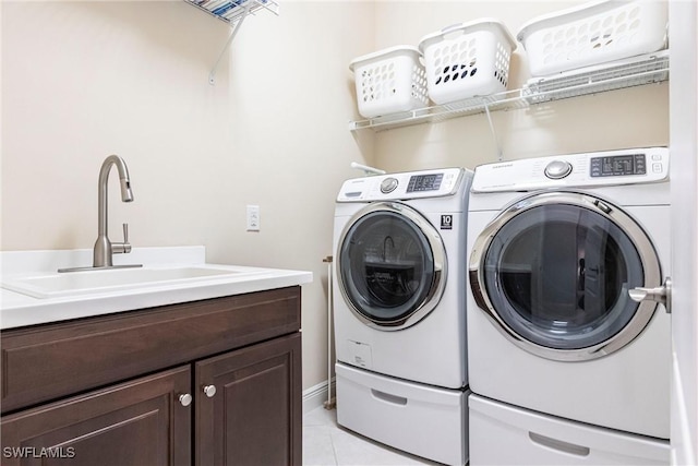 clothes washing area with light tile patterned floors, independent washer and dryer, a sink, and cabinet space