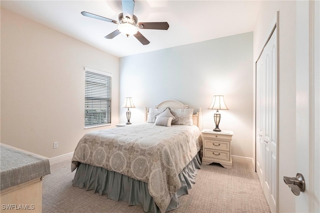 bedroom with a ceiling fan, a closet, light colored carpet, and baseboards