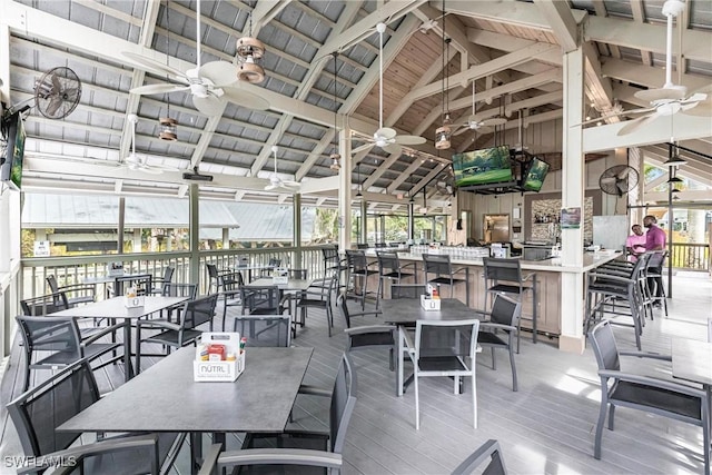 view of patio / terrace featuring a deck, outdoor dry bar, a ceiling fan, and outdoor dining space