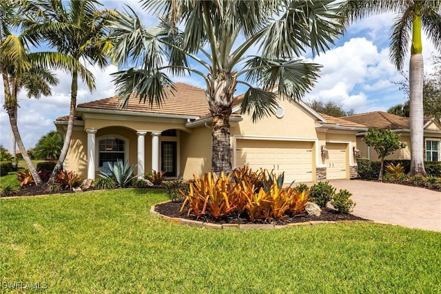 mediterranean / spanish-style home featuring a garage, a tiled roof, decorative driveway, stucco siding, and a front lawn