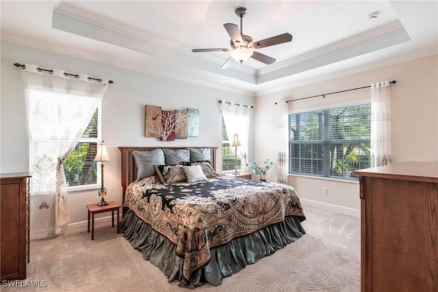 bedroom featuring light carpet, a tray ceiling, and baseboards