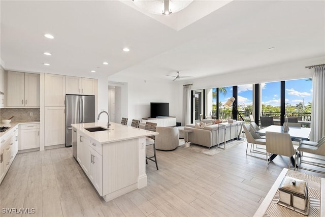 kitchen featuring a sink, appliances with stainless steel finishes, light countertops, decorative backsplash, and ceiling fan