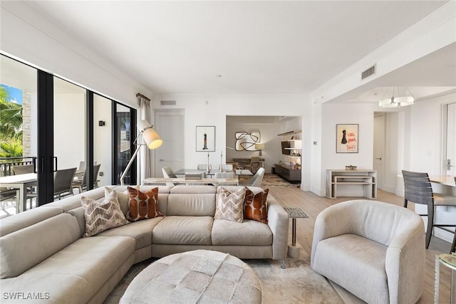 living room featuring visible vents, an inviting chandelier, and light wood-style flooring