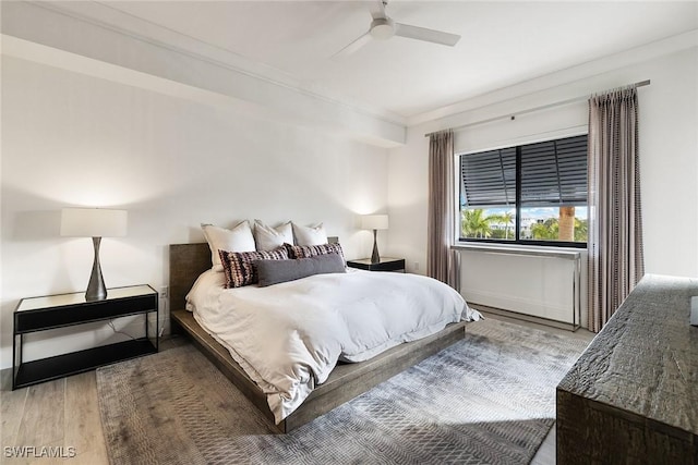 bedroom with ceiling fan, wood finished floors, and ornamental molding