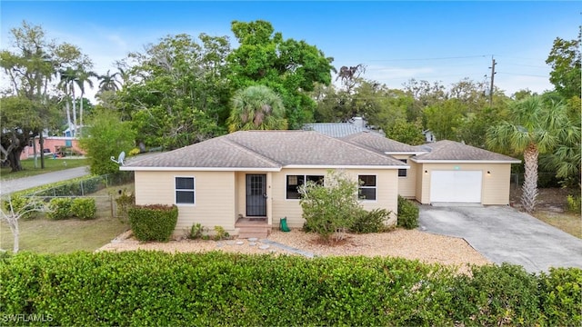 single story home featuring a garage, driveway, and fence