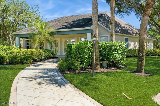 view of front of property featuring stucco siding, driveway, a front lawn, french doors, and a shingled roof