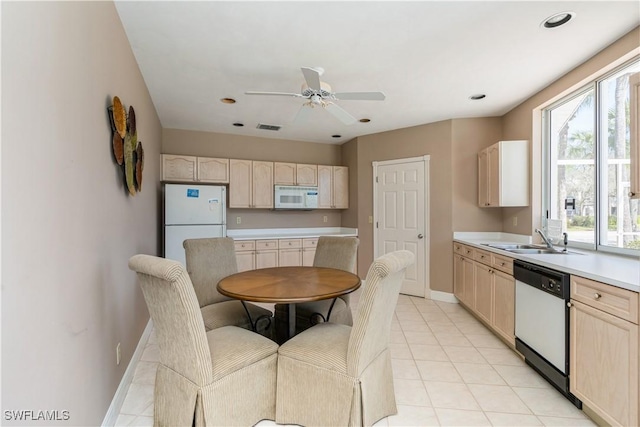 kitchen with white appliances, baseboards, light brown cabinetry, a sink, and light countertops